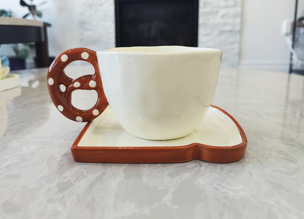 Biscuit and Toast Cup Set - Ceramic cup with a decorative handle on a matching coaster on a marble surface.