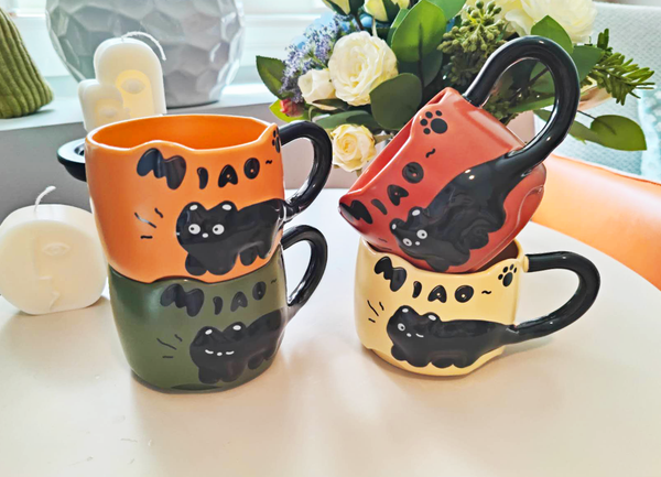 Black Cat Embossed Ceramic Mug - Colorful mugs with cat designs on a light surface.