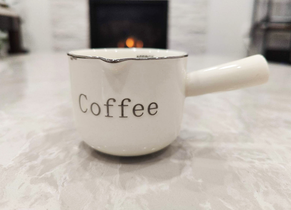 Ceramic Creamer Pitcher | Mini Milk Jug - White mug with 'Coffee' text on a fluffy surface